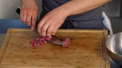 Chef Cutting Raw Meat on Wooden Board