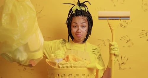 Satisfied Dark Skinned Woman Housekeeper Collects Garbage In House Does Spring Cleaning Holds Mop...