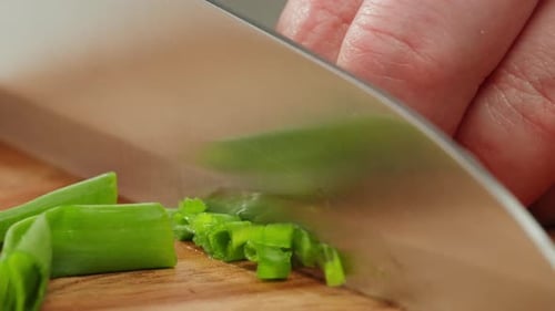Chef Cutting Bunch of Green Onion Feathers By Knife on a Cutting Board on Professional Restaurant