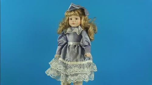 Poupée rotative en porcelaine antique fille Malvina sur fond bleu.