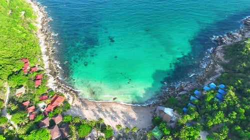 Sandy beach shore with beautiful resort surrounded by clear sea water.