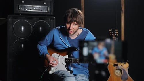 Man Playing Electric Guitar Records Performance on Phone