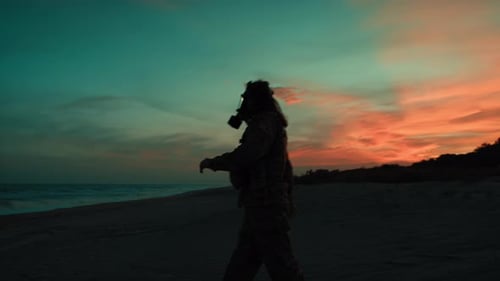 Un soldado con máscara antigás camina por una playa contaminada por radiación nuclear