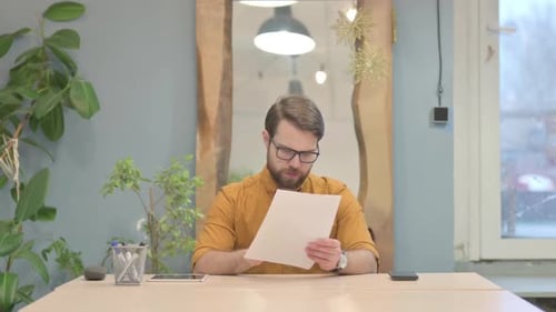 Young Businessman Reading Documents in Office
