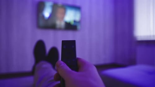 Person Relaxes, Watching TV With Remote Control