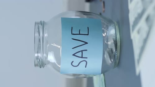 Money Being Placed in Savings Jar