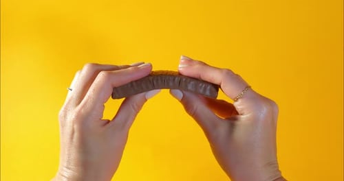 Breaking Protein Bar in Half on Yellow Background