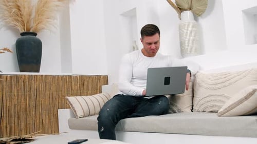 Man Using Laptop on Sofa Indoors