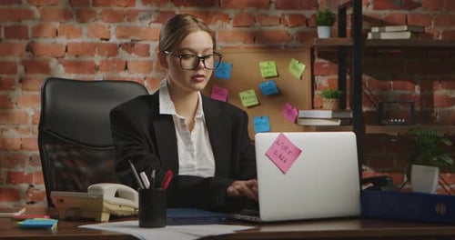 Young Businesswoman in Office with Brick Wall Background