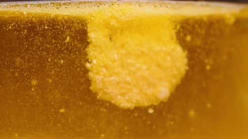 A partially dissolved Effervescent Tablet disperses, forming a cloudy, bubbling pattern in a Yellow