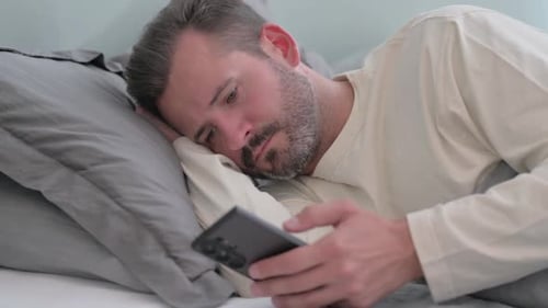 Man Lying in Bed Using a Cell Phone