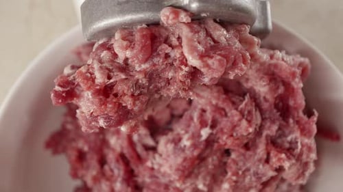 Macro shot of red beef minced meat coming out of electric grinder
