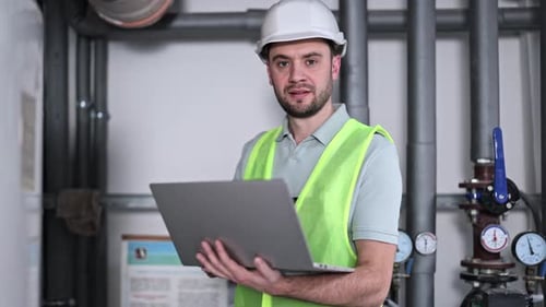 Engineer With Laptop Inspecting Pipes