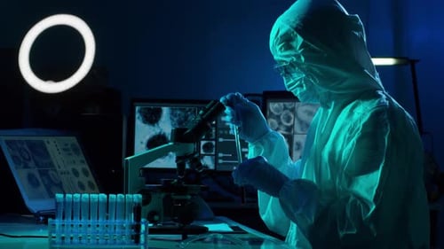 Scientist in Hazmat Suit Works with Microscope