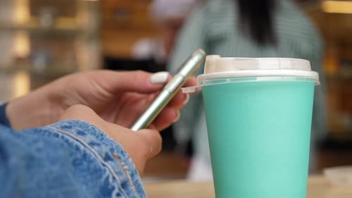Closeup of a Woman with a Phone in Her Hands Sitting in a Coffee Shop