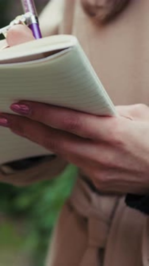 Woman Writes in Notebook Outdoors