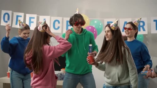 A Group of Colleagues in Festive Hats and Glasses are Dancing Having Fun Celebrating a Common