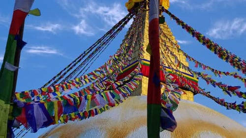 Lines of prayer flags blowing in the wind with the golden Boudhanath stupa temple in Kathmandu Nepal