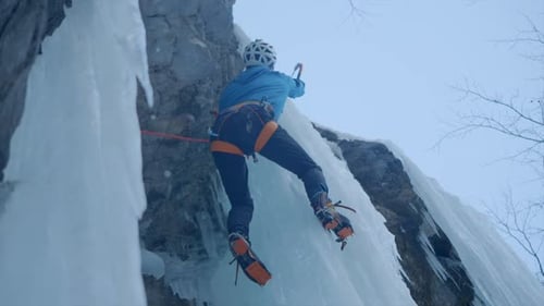 Slow Motion Rear Shot Of Professional Climber Wearing Helmet On Glacier Using Axe