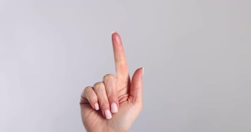 Woman pointing at something on light grey background, closeup