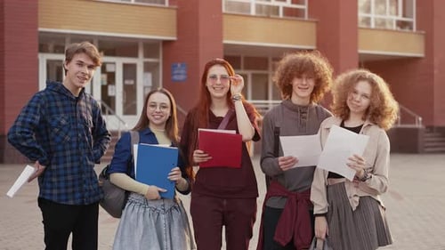 Smiling Students Standing Outside School Building with Notebooks