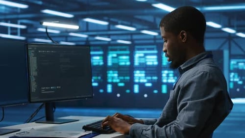 Young Man Coding at Desk in Modern Office