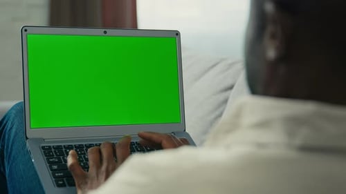 Man Typing on Laptop with Green Screen