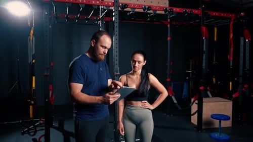 Man and Woman Discussing Fitness Plan on Tablet