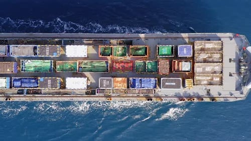 Frachtschiff beladen mit bunten Containern und großen Kisten auf See.
