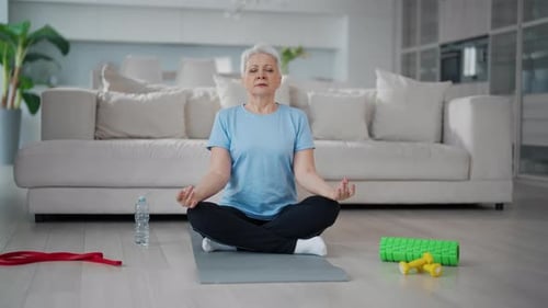 Senior Woman Meditating at Home on Yoga Mat