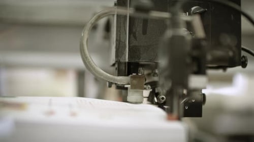 Close up of one part of a printing machine, pressing down on paper pile and separating one sheet of