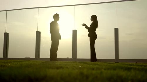 Silhouetted Business People Meeting on Rooftop at Sunset