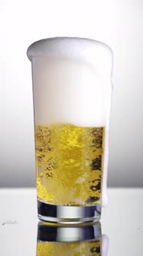 Beer is Poured into Glass with Foamy Head