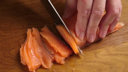 Hands Slicing Fresh Salmon on Cutting Board