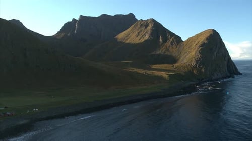 Epic scene of sharp sloping mountain peaks and ocean on a bright clear day drone shot