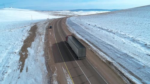 Aerial Shot of a Lorry Truck Driving on an Intercity Road Among the Fields Covered with Snow Winter