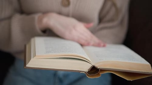 Partial View of Woman Hand Flipping Book Page in CloseUp Reading Scene