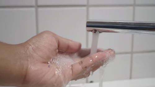 Hand Washing Under Silver Faucet Close Up