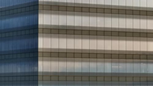 Closeup of Corner of Modern Corporate Office Building with Glass Windows Reflecting the Sky