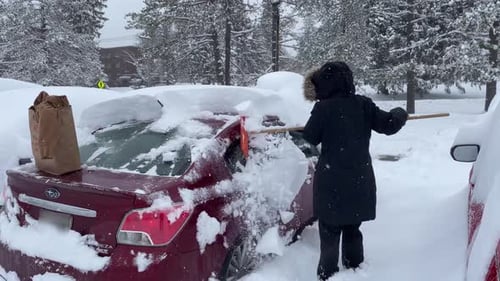 Person Shoveling Snow Off Car After Snowfall