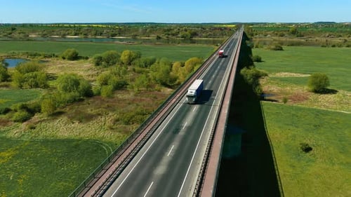 Heavy Duty Truck with Cargo Trailer Driving Across Bridge Through Countryside Landscape Freight
