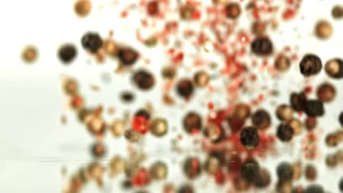 Falling multicolored peppercorns and red pepper flakes macro