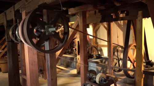 Handheld Wide shot inside old heritage Mill - spinning wheels with transmission