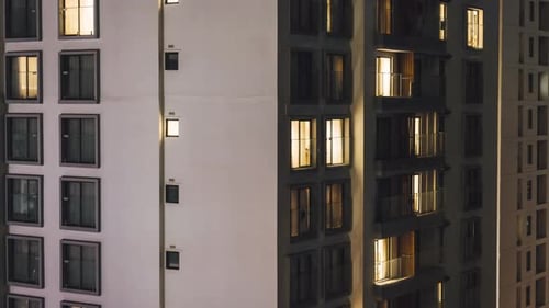 Fenster von Wohngebäuden im nächtlichen Zeitraffer. Lichter schalten sich ein und aus.