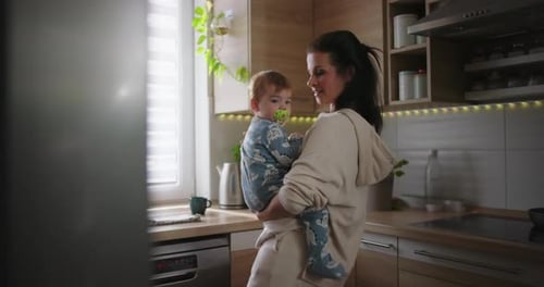 Woman holding baby in modern kitchen at home