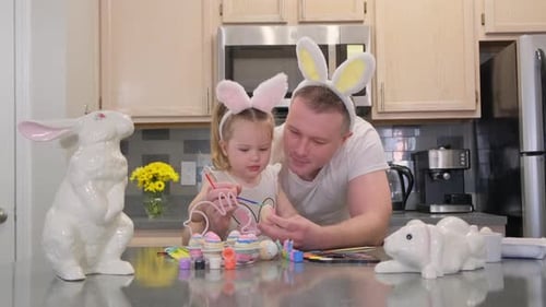 Child and Adult Painting Easter Eggs at Home