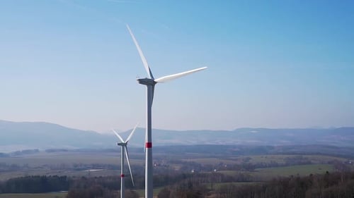Windmühlen in Feldern mit Hügeln im Hintergrund - Panoramaaufnahme in slowmo