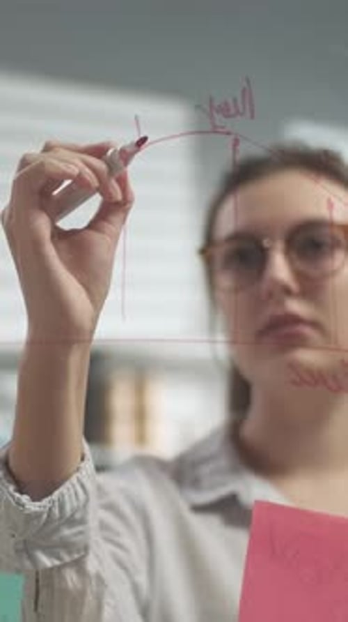 Woman Writing on Glass Board in Office