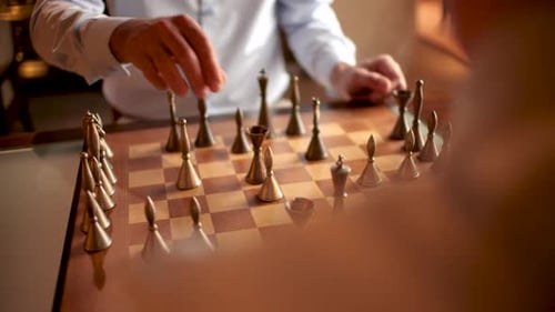 Two men in a shirt playing chess with a luxury chess set at night.
