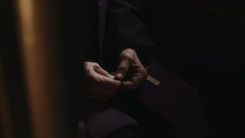 Hands of Priest Holding Rosary Beads Inside of Confession Booth